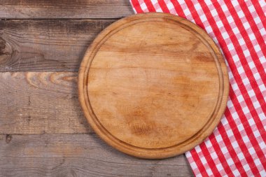 Round kitchen stand for cutting products and a red and white towel on a wooden background