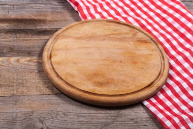 Round kitchen stand for cutting products and a red and white towel on a wooden background