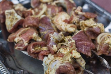 Pieces of raw pork meat on skewers, cooking meat on a fire.