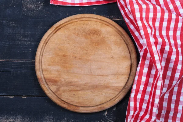 Round kitchen stand for cutting products and a red and white towel on a wooden background