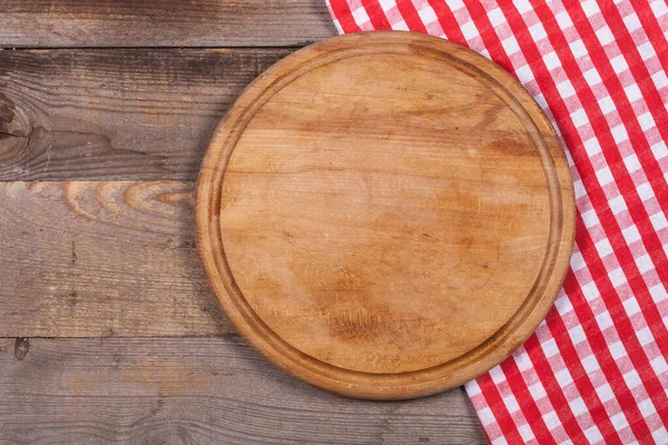 Round kitchen stand for cutting products and a red and white towel on a wooden background