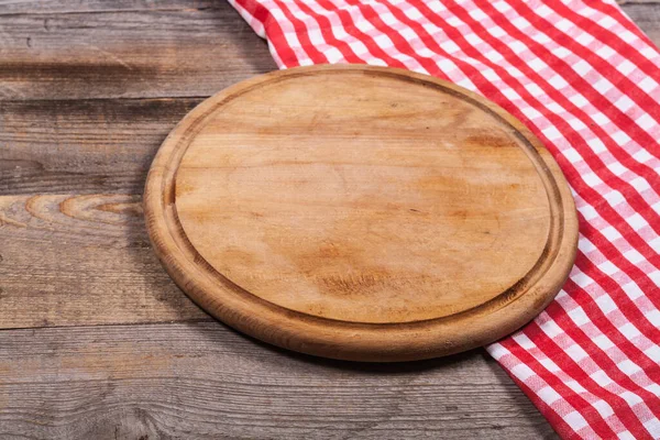 Round kitchen stand for cutting products and a red and white towel on a wooden background