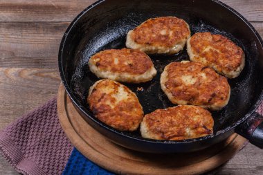 Fried chicken cutlets on a black frying pan close-up, fried meat products, home cooking