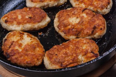 Fried chicken cutlets on a black frying pan close-up, fried meat products, home cooking