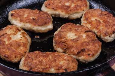 Fried chicken cutlets on a black frying pan close-up, fried meat products, home cooking