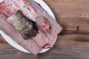 Büyük balıktan doğranmış et. Mutfak masasındaki beyaz tabakta gümüş sazan filetosu. Yakın plan, üst manzara.