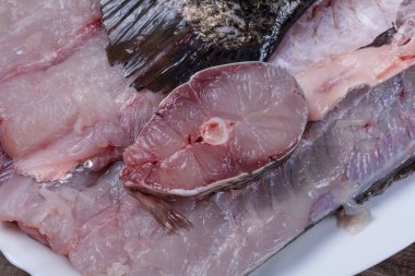 Büyük balıktan doğranmış et. Mutfak masasındaki beyaz tabakta gümüş sazan filetosu. Yakın plan, üst manzara.