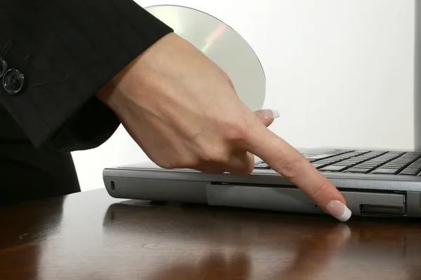 Рука женщины помещает DVD в ноутбук за столом — стоковое фото