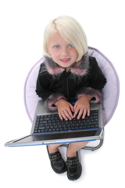 Vacker liten flicka i stolen med bärbar dator — Stockfoto
