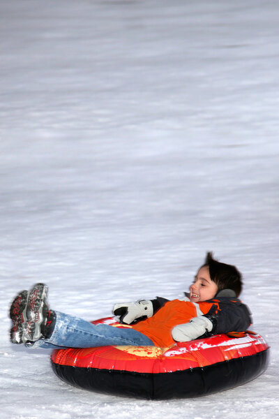 Boy Tubing Down Snowy Hill.