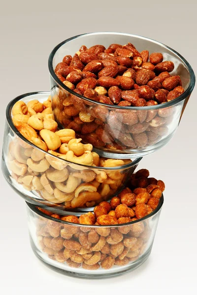 Three glass bowls filled with cashews, salted roasted almonds an — Stock Photo, Image
