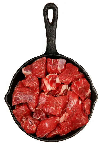 Cubos de carne cruda picados en sartén de hierro fundido sobre blanco — Foto de Stock