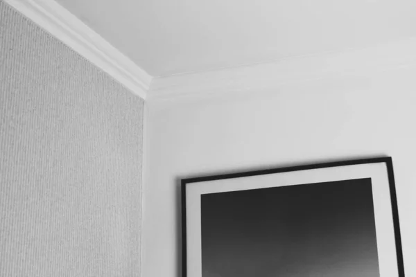 Siyah bir tablo beyaz bir duvarda asılı.