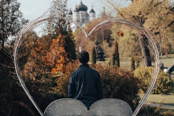 a man stands in a frame in the shape of a heart