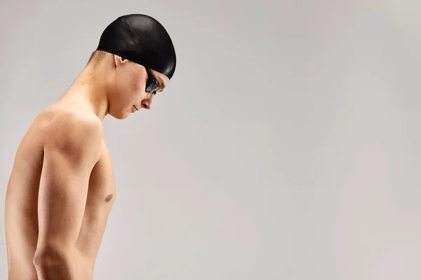 Hombre atlético joven listo para saltar a la piscina sobre fondo gris. El concepto de natación y juegos de agua. — Foto de Stock