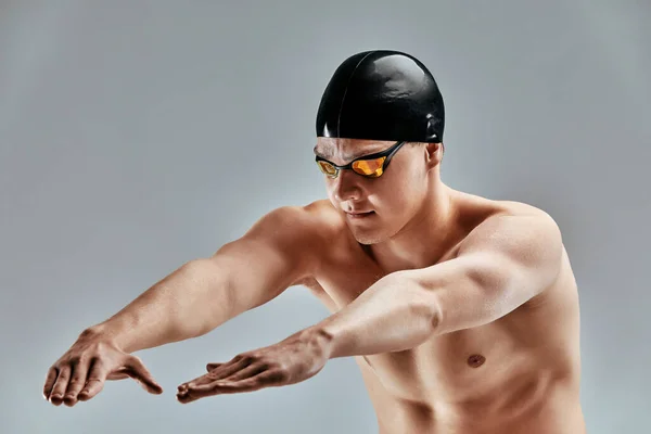 年轻的运动员准备在灰暗的背景下跳进游泳池.游泳和水上运动的概念. — 图库照片