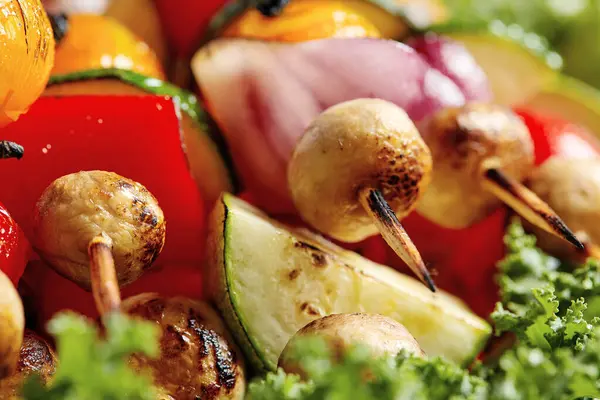 Espetos vegetarianos com ervas secas em espetos de madeira de cogumelos de cebola de tomate de abobrinha em uma chapa — Fotografia de Stock