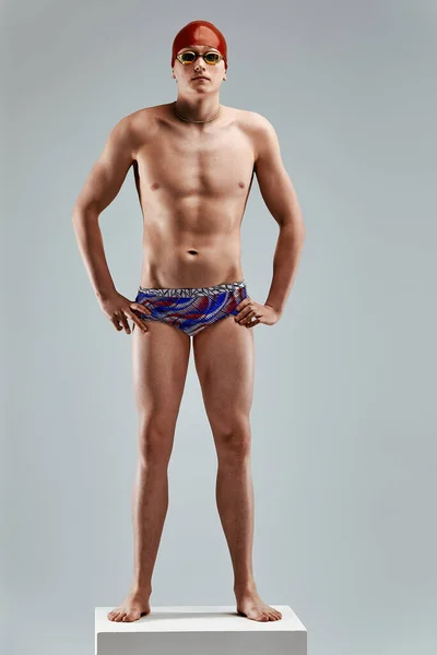 Homem atlético jovem pronto para saltar na piscina contra fundo cinza. O conceito de natação e jogos de água. — Fotografia de Stock