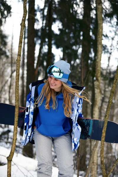 Bild mit einem Porträt einer Snowboarderin, die einen Helm mit einem hellen Spiegelbild in der Brille trägt. Vor dem Hintergrund eines hohen Schneeberges — Stockfoto