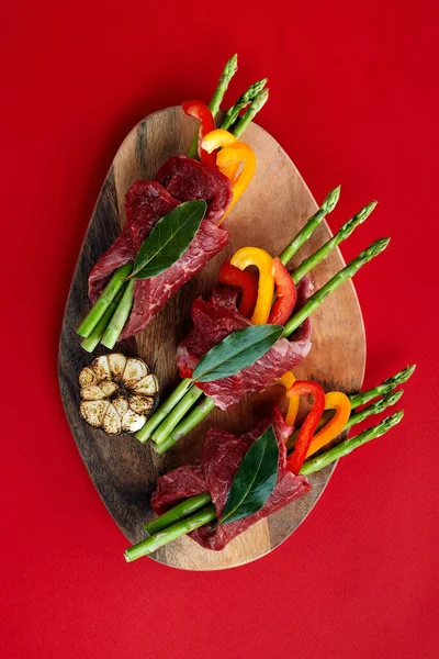 Rulades de carne cruda y guarniciones de verduras frescas listas para cocinar sobre un fondo blanco —  Fotos de Stock