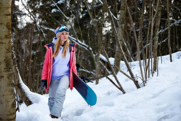 Bild mit einem Porträt einer Snowboarderin, die einen Helm mit einem hellen Spiegelbild in der Brille trägt. Vor dem Hintergrund eines hohen Schneeberges — Stockfoto