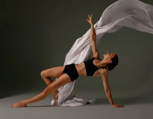 Bailarina de Ballet Emocional Femenina en Traje Corporal y Material Volador Posando en Danza en Varias Posadas Contra el Fondo Gris —  Fotos de Stock