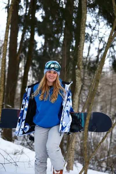 Zamknij portret kobiety snowboardzistki w ośrodku narciarskim w kasku i goglach z odbiciem lasu w górach. Darmowe miejsce do kopiowania informacji. — Zdjęcie stockowe