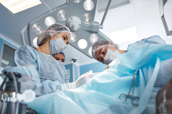 Koncentrerad kirurgiska team drift en patient i en operation teater. Välutbildade anestesiolog med år av träning med komplexa maskiner följer patienten genom hela operationen — Stockfoto