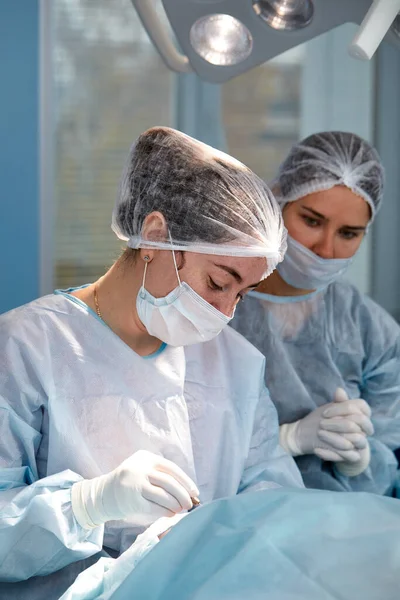 Equipo quirúrgico concentrado operando a un paciente en un quirófano. Anestesiólogo bien entrenado con años de entrenamiento con máquinas complejas sigue al paciente durante toda la cirugía — Foto de Stock