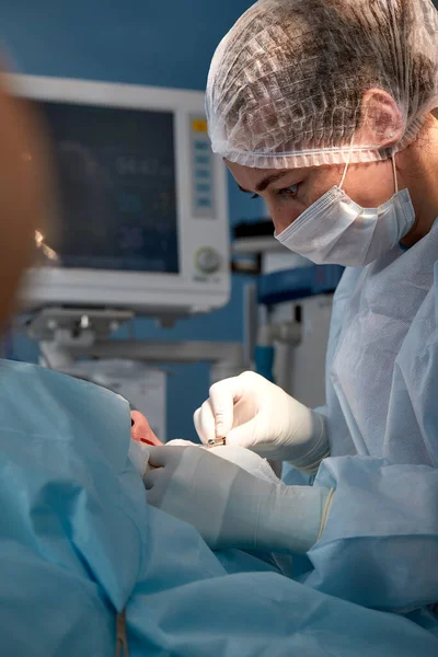 Primer plano de la cara de un paciente que se somete a una blefaroplastia. El cirujano corta el párpado y realiza manipulaciones utilizando instrumentos médicos — Foto de Stock