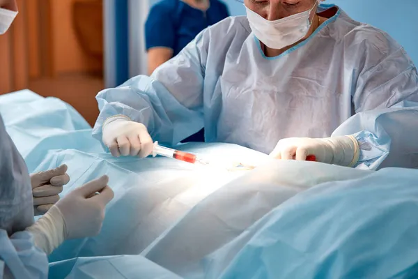 Perspectiva de una paciente en una mesa de operaciones que ve al médico arriba con una jeringa en la mano. Enfoque selectivo — Foto de Stock