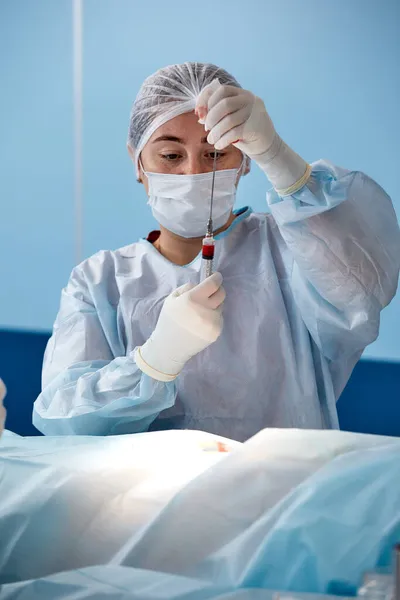 Perspectiva de una paciente en una mesa de operaciones que ve al médico arriba con una jeringa en la mano. Enfoque selectivo — Foto de Stock