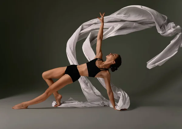 Bailarina de Ballet Emocional Femenina en Traje Corporal y Material Volador Posando en Danza en Varias Posadas Contra el Fondo Gris —  Fotos de Stock