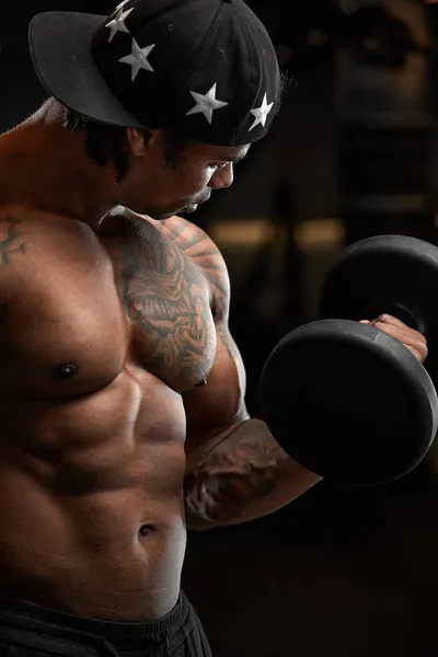 Stark och muskulös mörk hud mannen tränar på modern utrustning i gymmet. Porträtt av muskulös pumpas upp fitness trainer — Stockfoto