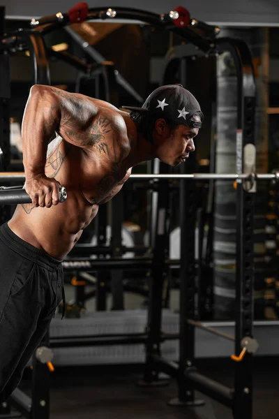 Stark och muskulös mörk hud mannen tränar på modern utrustning i gymmet. Porträtt av muskulös pumpas upp fitness trainer — Stockfoto
