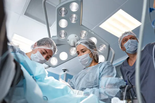 Concentrated Surgical team operating a patient in an operation theater. Well-trained anesthesiologist with years of training with complex machines follows the patient throughout the surgery — Stock Photo, Image