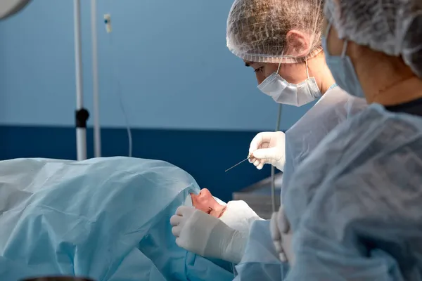 Close up da face de um paciente que está sendo submetido a blefaroplastia. O cirurgião corta a pálpebra e realiza manipulações usando instrumentos médicos — Fotografia de Stock