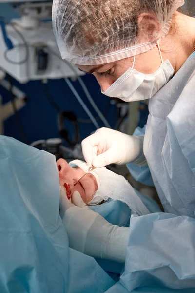 Nahaufnahme des Gesichts eines Patienten, der sich einer Blepharoplastik unterzieht. Der Chirurg schneidet das Augenlid und führt Manipulationen mit medizinischen Instrumenten durch — Stockfoto