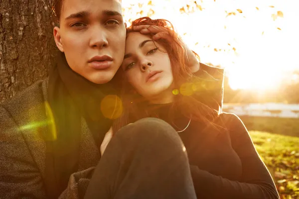 Pareja joven enamorada caminando en el parque de otoño cogida de la mano mirando al atardecer —  Fotos de Stock