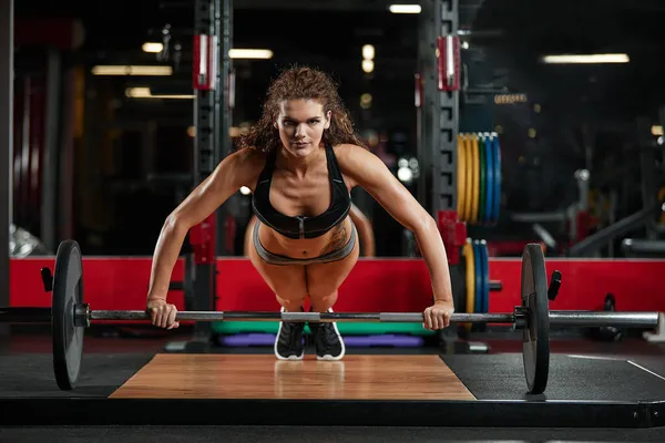 Attraente donna in forma si allena con i manubri come un concetto di fitness su sfondo scuro . — Foto Stock