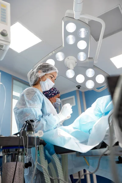Equipo quirúrgico concentrado operando a un paciente en un quirófano — Foto de Stock