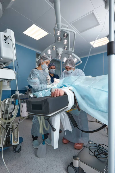 Concentrated Surgical team operating a patient in an operation theater. Well-trained anesthesiologist with years of training with complex machines follows the patient throughout the surgery — Stock Photo, Image