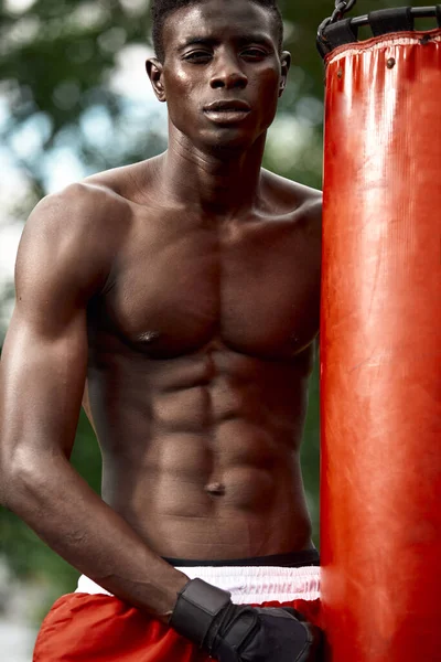 Front view of muscular black boxer punching towards camera with a deep and intense face outdoor. Boxing and Training Concept — Stock Photo, Image