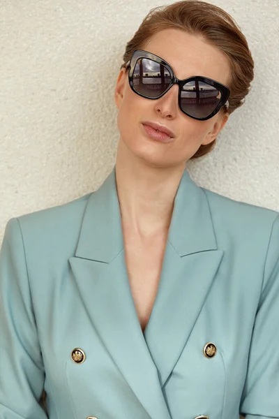 Hermosa joven con gafas de sol en una chaqueta de moda pasea por la ciudad. Retrato de estilo de vida al aire libre. — Foto de Stock