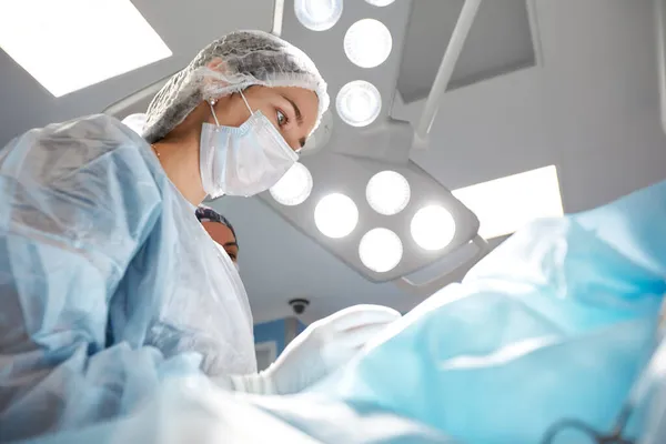 Primer plano de una cirujana en un quirófano, un médico con expresión tensa en la cara, en un quirófano. — Foto de Stock