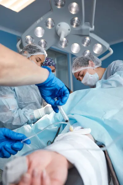 Concentrated Surgical team operating a patient in an operation theater. Well-trained anesthesiologist with years of training with complex machines follows the patient throughout the surgery — Stock Photo, Image