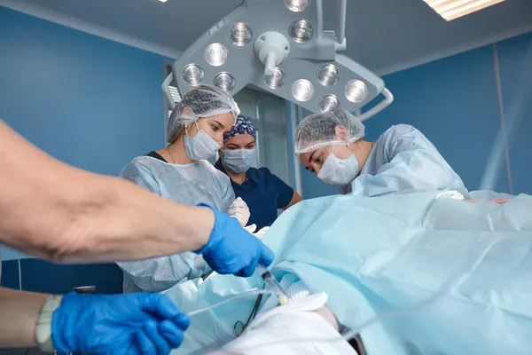 Концентрована хірургічна команда, яка керує пацієнтом в операційному театрі. Добре підготовлений анестезіолог з роками тренувань зі складними машинами стежить за пацієнтом протягом всієї операції — стокове фото