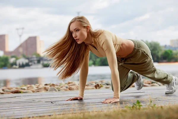 Blonde junge, athletische Frau beim Training in einem Park in einer städtischen Umgebung. Attraktive athletische Frau, die morgens im Freien trainiert, kopiert Raum. Gesundheit, Fitness-Konzept — Stockfoto