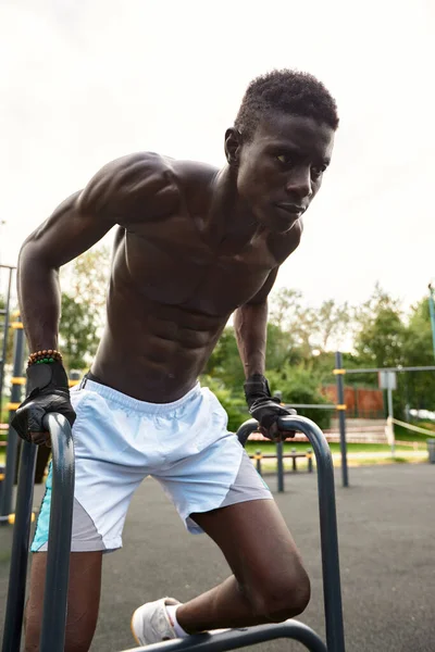 Un africano musculoso haciendo flexiones en el parque. Fuerte atleta masculino haciendo ejercicio al aire libre. — Foto de Stock