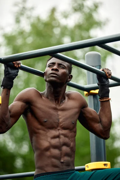 Un africano musculoso haciendo flexiones en el parque. Fuerte atleta masculino haciendo ejercicio al aire libre. — Foto de Stock